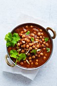 Chickpeas soaking in a bed of onion tomato sauce, garnished with coriander leaves and ginger juliennes