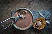 Chocolate icecream and scoop with walnut cornet on slate board over wooden background