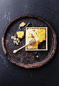 Honeycomb with wooden honey dipper on black textured background
