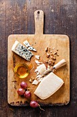 Käse mit Honig, Nüssen und Trauben auf Holzschneidebrett