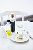 Fresh buffalo mozzarella ball with olive oil, basil and balsamic on white table