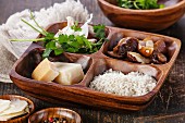 Zutaten für Pilzrisotto: Reis, Parmesan, Knoblauch, Petersilie und Pilze in einer Holzschale