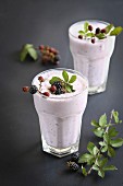 Two glasses with blackberry smoothie decorated with fresh blackberries