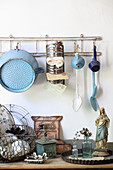 Old kitchen utensils hung from rod above Madonna figurine