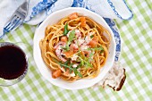 Pasta with prawns, salmon, rocket, black pepper and a glass of red wine and bread