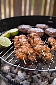 Hamburgers, meat skewers and lime halves on a barbeque