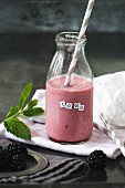 Blackberry smoothie in a bottle with mint and a straw