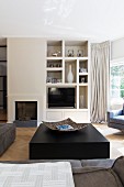 Solid black block as coffee table in front of fireplace and masonry shelves