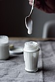Coconut yoghurt dripping from a spoon into a glass
