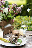 Besteck im Serviettenring aus Korb auf rustikalem Gartentisch