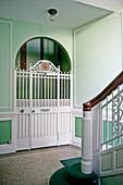 Old grille on doors of lift in green stairwell of period building