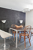 Various chairs around dining table in front of black wall