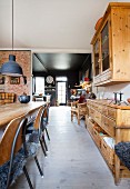 View past old wooden furniture in dining room into black kitchen