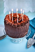 Chocolate birthday cake with 8 lit candles on cake stand