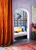 View through a passage into a niche with a sofa and screen