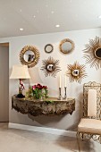 Antique wall-mounted console below various sunburst mirrors