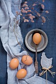 Hen ornament, eggs, vintage spoon and pewter plate on blue fabrics