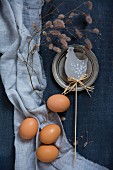 Eggs, hen ornament and pewter plate on blue fabrics