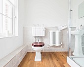 A bright guest bathroom with pedestal WC and low shelf