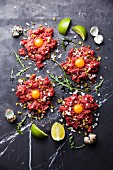 Beef tartare steak with pickled cucumber and onion on dark marble background