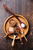 Different types of food coarse Salt in wooden spoons on dark background
