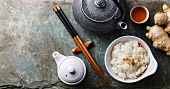 Steamed rice in bowl and green tea on stone slate background