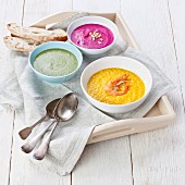 Three different coloured soups on a tray