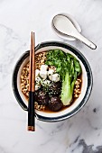 Miso Ramen Asian noodles with shiitake, tofu and pak choi cabbage in bowl on white marble background