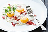 Traditional breakfast with eggs and bacon on white plate