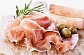 Ham with olives on wooden background