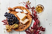 Parmesan cheese and grapes on olive wood plate and wine