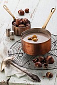 Chestnut soup in copper pot with roasted chestnuts on blue textural background