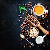 Tasse Kaffee, Kaffeebohnen, braune Zuckerwürfel und Milchkännchen
