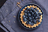 Top view on blueberry tart served on blue ceramic plate over textile napkin