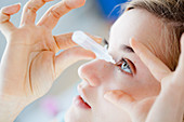 Woman applying eye-drops into her eye