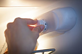 Woman setting refrigerator thermostat