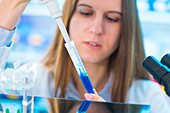 Young woman using pipette with blue liquid