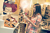 Young woman looking at shoes in shop