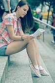 Young woman sitting on steps reading notes