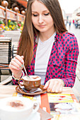 Young woman with hot drink at outdoor cafe