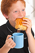 Boy eating food and holding mug