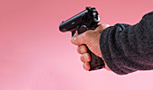 Person holding handgun against a pink background