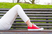 Woman lying on a bench wearing red pumps