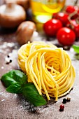 Frische Spaghetti und italienische Zutaten auf einem Holzbrett