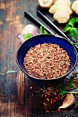 Wild rice in ceramic bowl and asian ingredients on wooden background