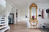 Baroque gilt-framed mirror and console table in hallway