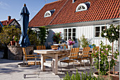 Long table and chairs on sunny terrace outside house