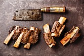 Beef Ribs BBQ and Butcher Meat cleaver on stone slate background