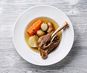 Stew soup khashlama with lamb, potatoes and carrot in plate on wooden background