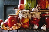 Einmachgläser mit Gemüse (Gurken, Tomaten, Paprika) und frische und getrocknete Äpfel